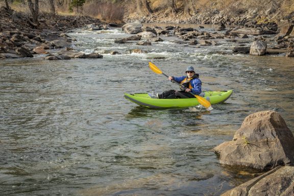 Kayaker paddling an inflatable kayak on a river